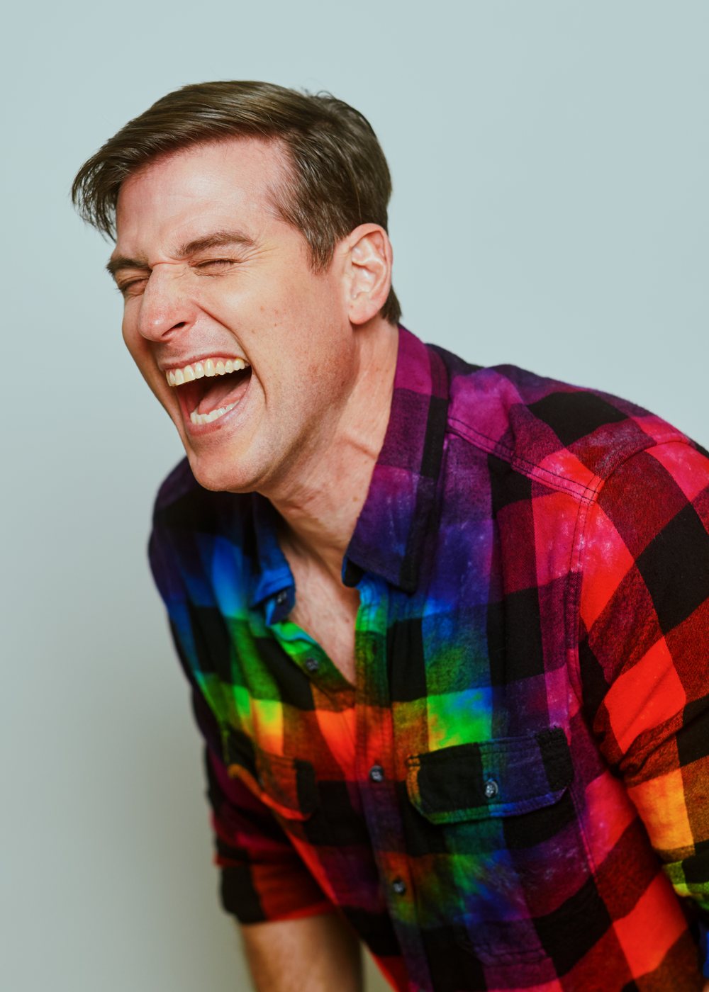 Jonathan Chase Greenfield laughing, in a bright plaid shirt