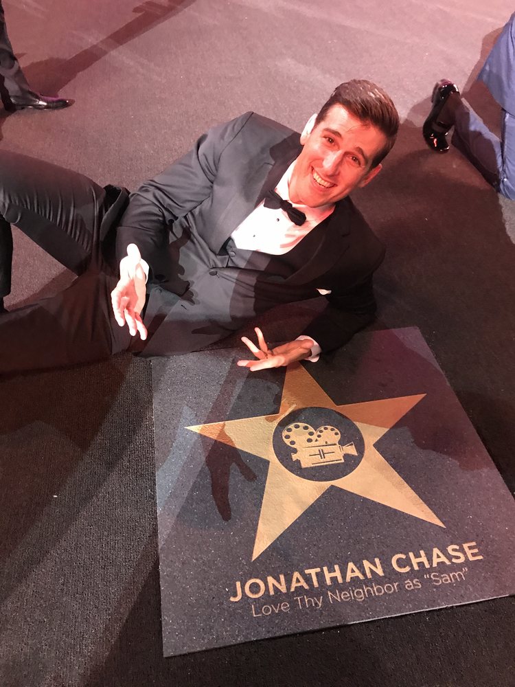 Jonathan lying beside a floor star reading Jonathan Chase, Love Thy Neighbor as Sam